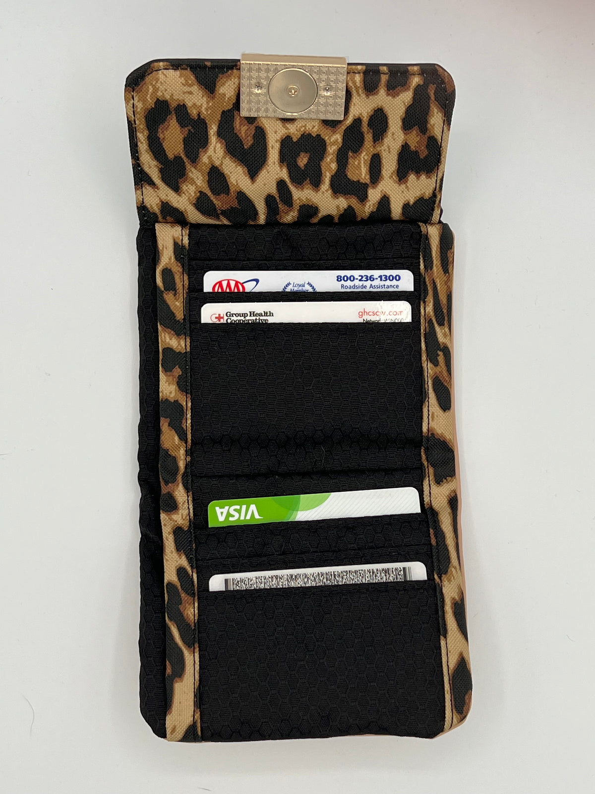 A leopard print black card holder wallet shown open, containing several sample credit cards, on a white background.